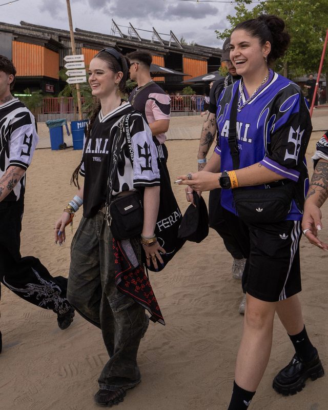 Two people walking across the festival sand, in the purple and the monochrome
