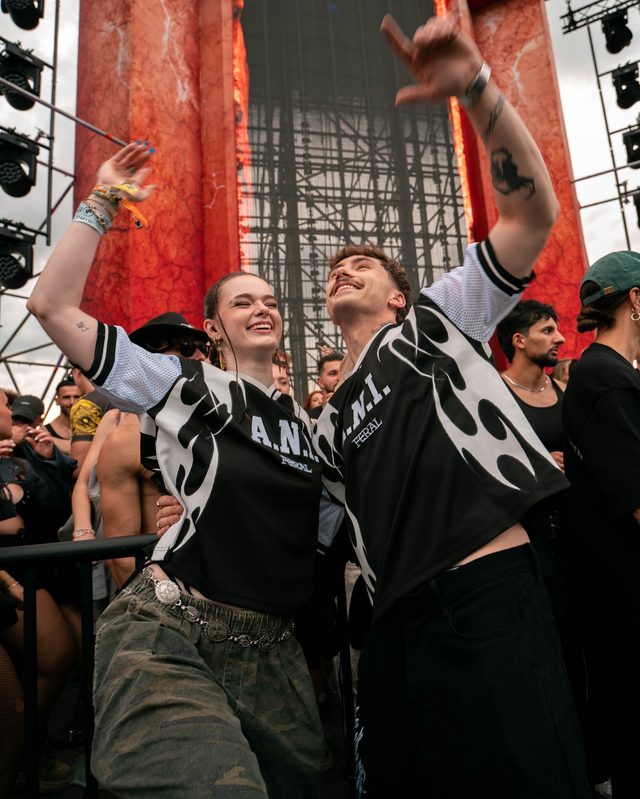 Two people in the monochrome jersey with their arms up beside the stage