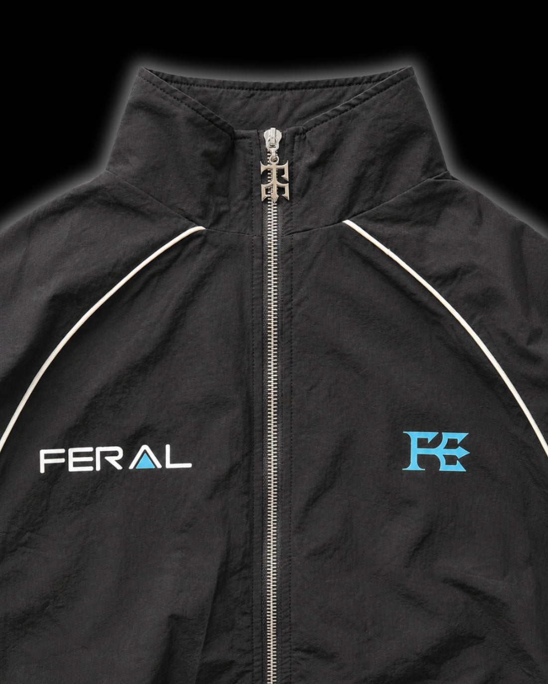 TRIBAL RACER WINDBREAKER blue close-up chest detail custom Feral hardware zip pull FERAL wordmark F monogram reflective piping high funnel collar