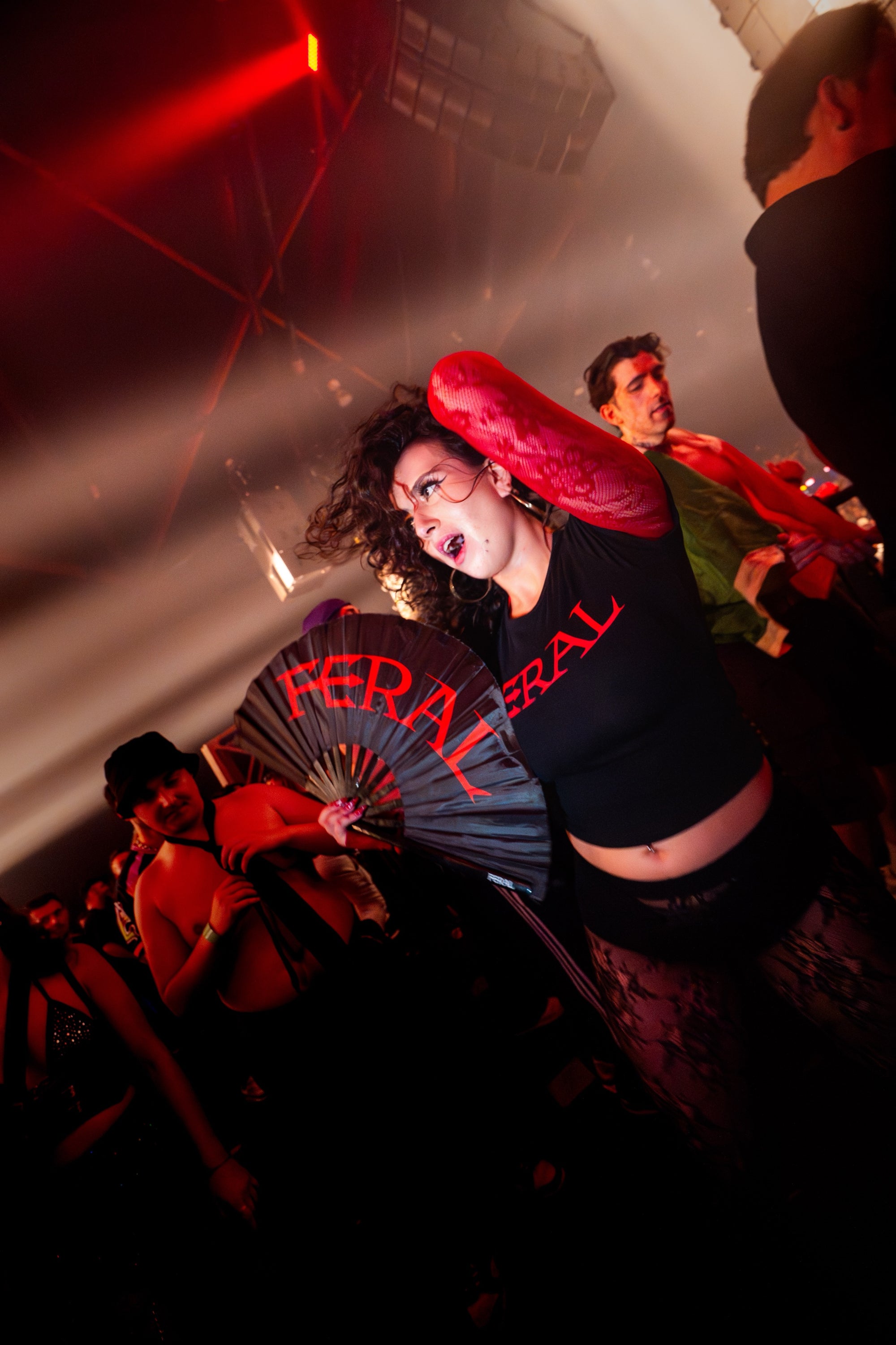 FERAL crimson baby tee on the dance floor with a FERAL hand fan