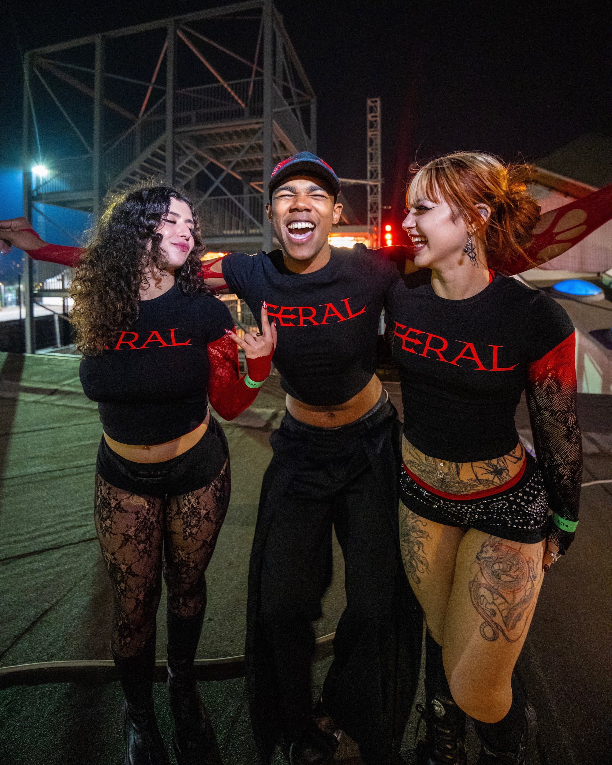 FERAL crimson baby tee on three friends at a night event