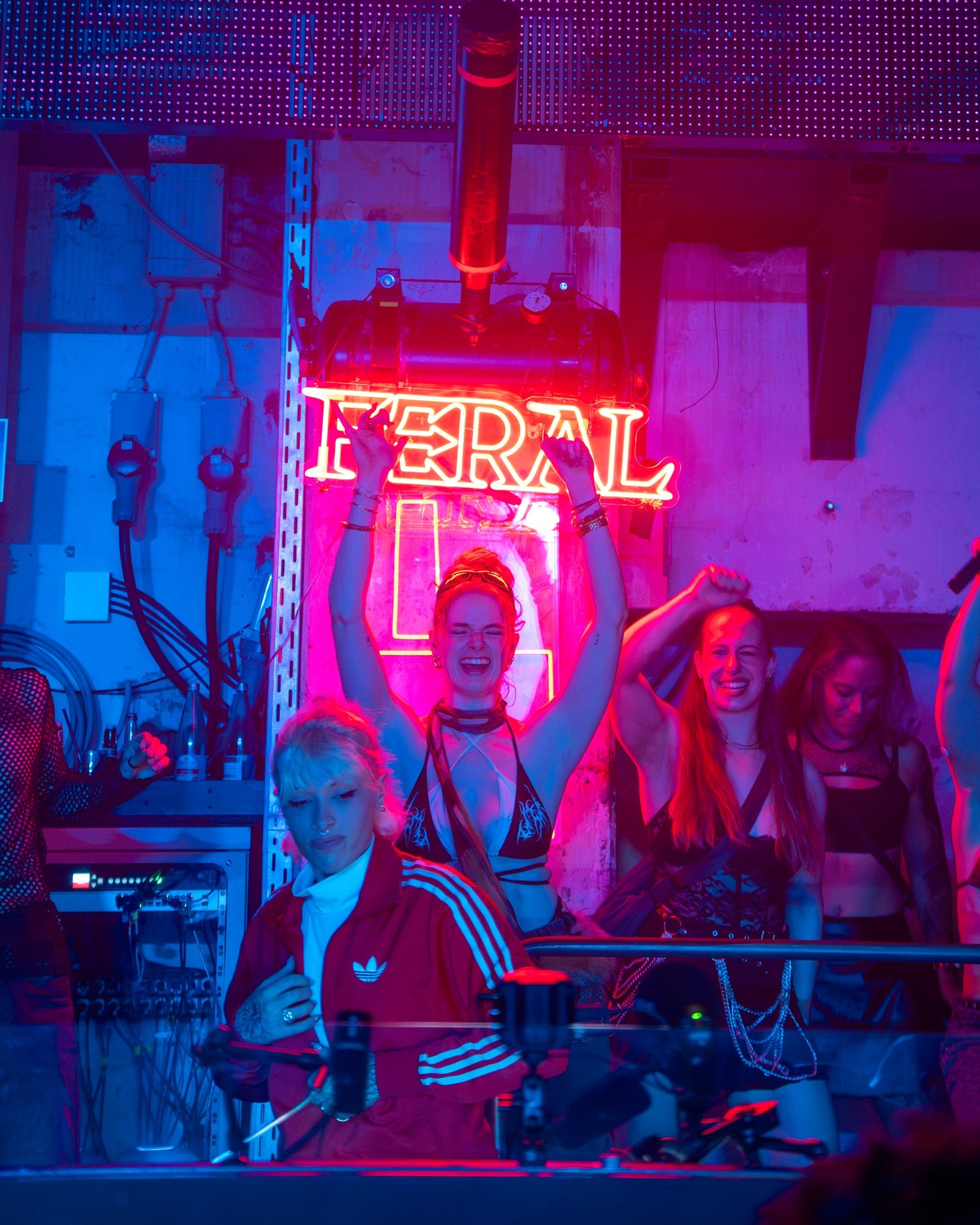 The FERAL neon sign behind the DJ booth with the crowd dancing under it