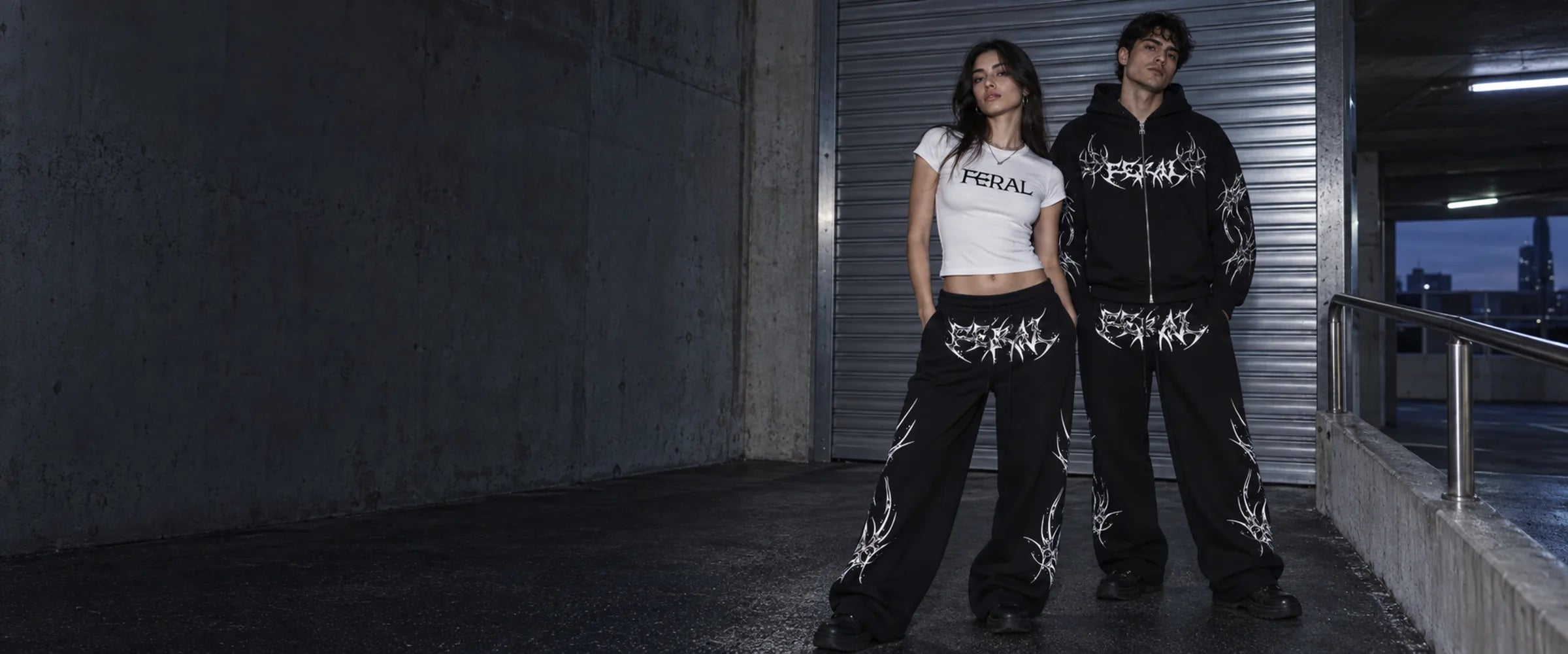 FERAL white baby tee and black ROGUE graphic zip hoodie styled with wide-leg sweatpants