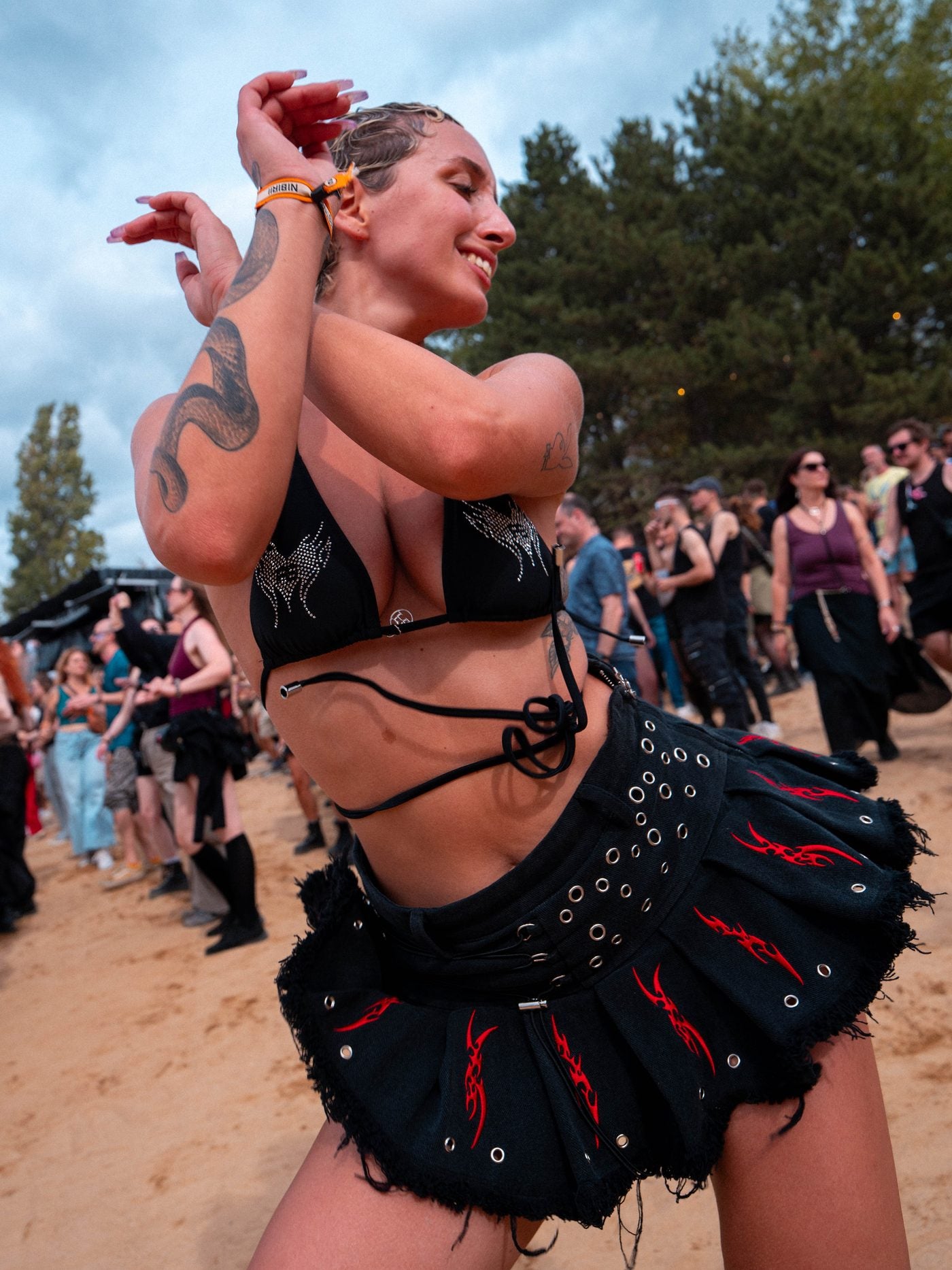 A girl dancing on the sand in the SIGILISM SKORT: metal eyelets, the lace-up, red sigils on the pleats