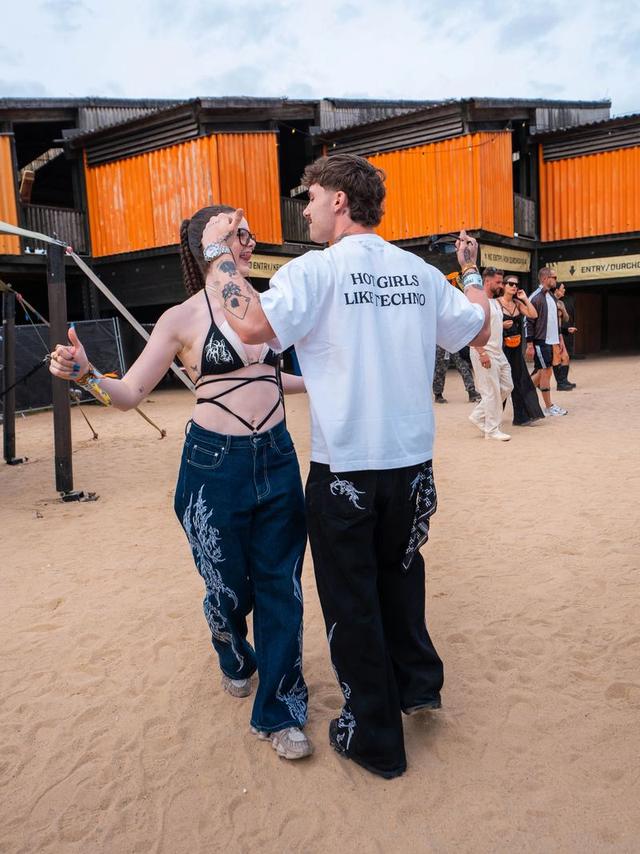 Two people dancing outside a festival stage, in denim blue and monochrome