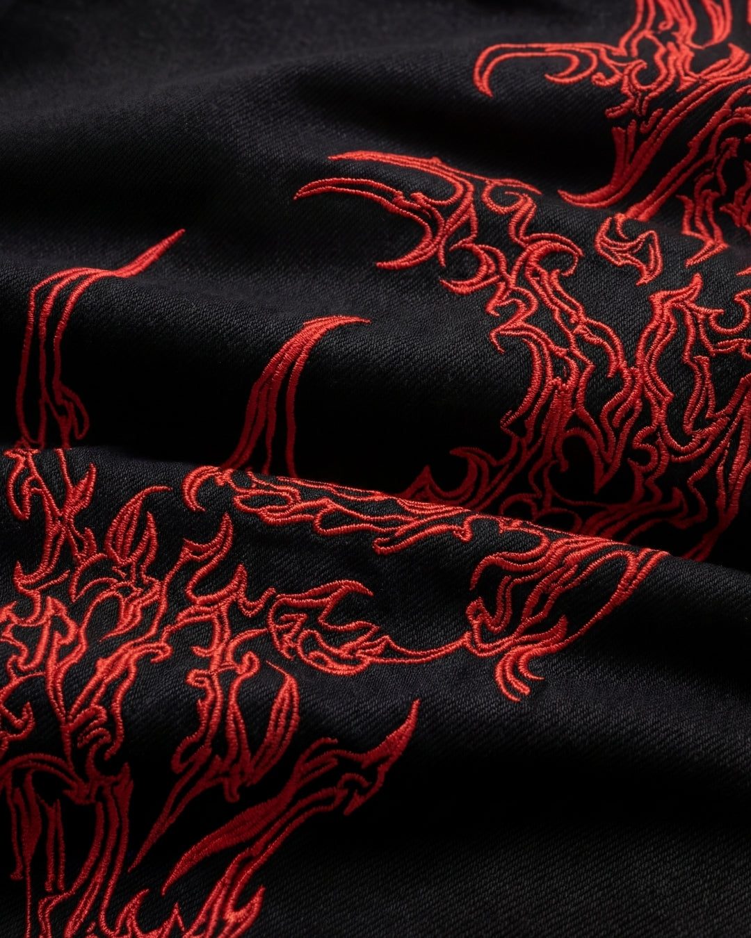Close up of the red sigilism embroidery on black denim